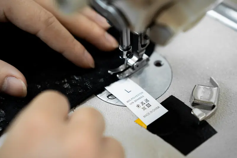 seamster attaching the tag on a completed custom black lingerie