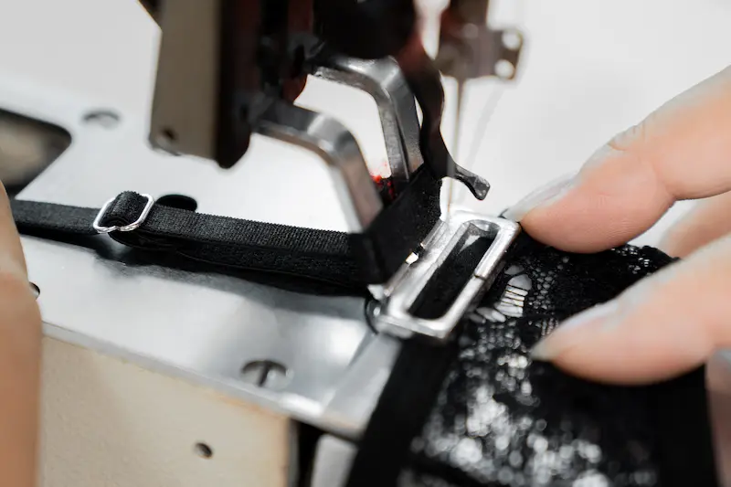 seamster attaching a black strap on the custom black lingerie